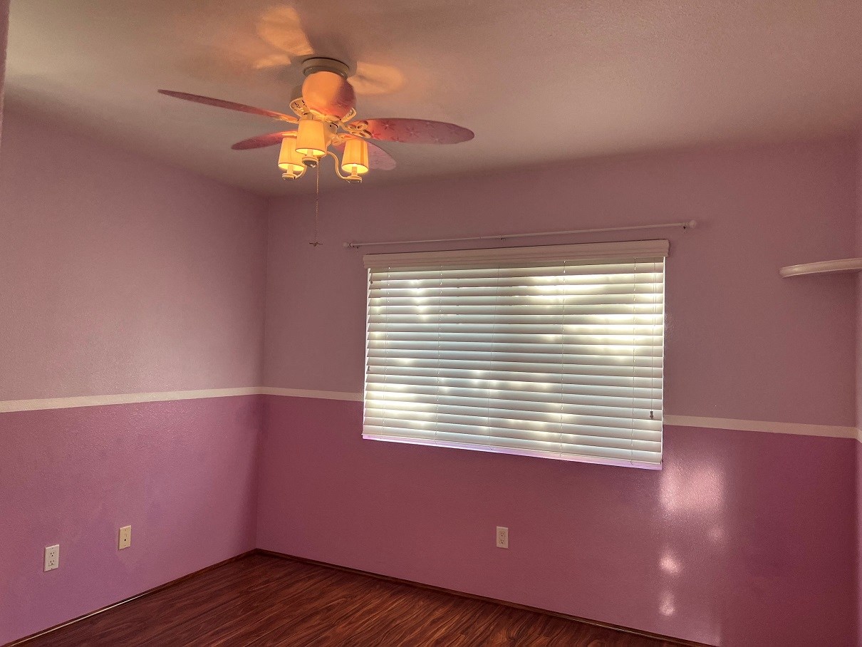 a room with pink walls and a ceiling fan and a window